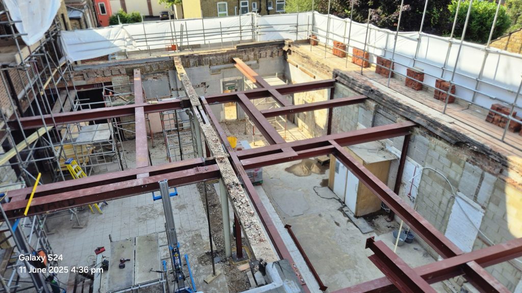 Structural steel fabrication and installation forming part of a load-bearing steel framework on a construction site.